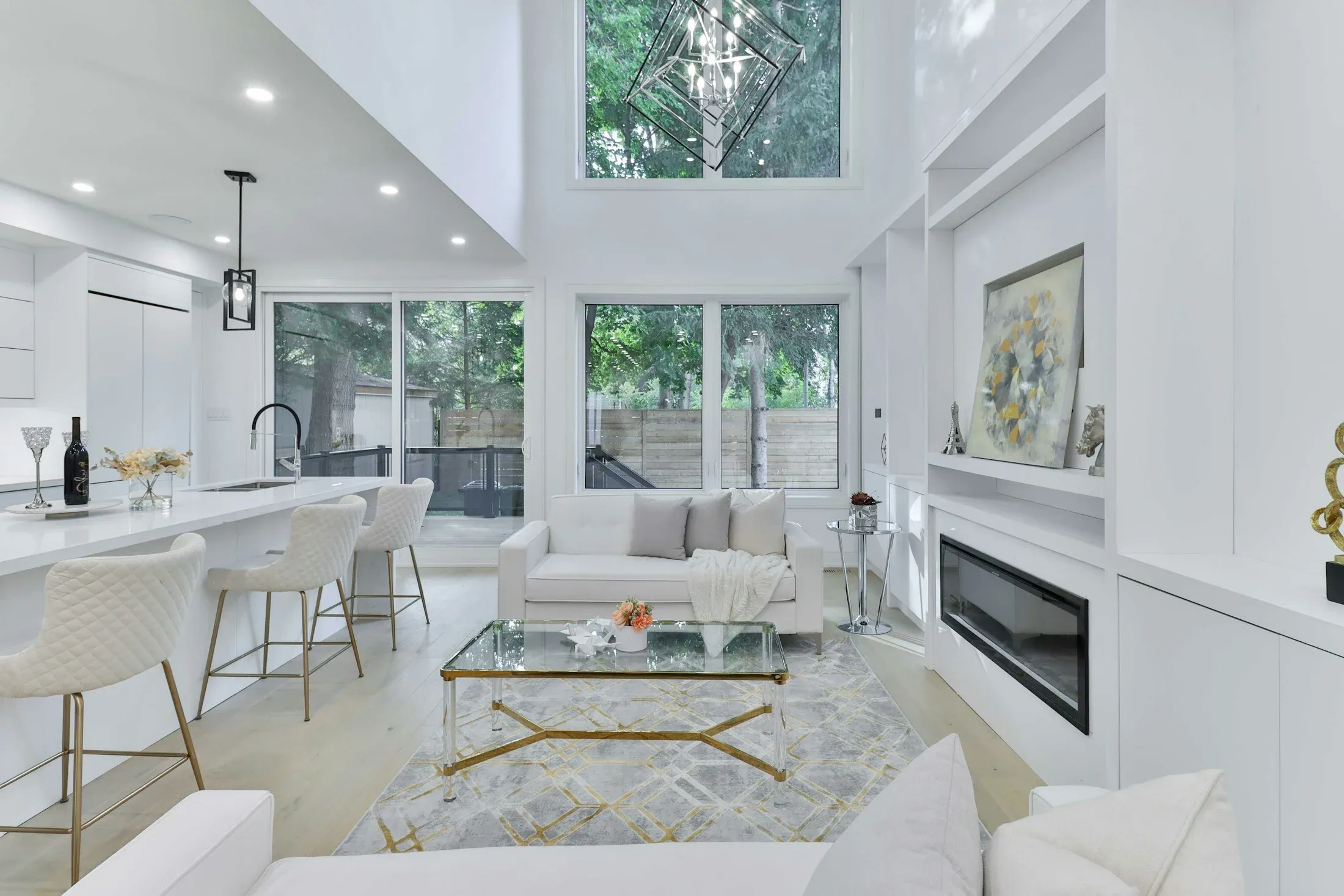 A light-filled living and dining area with tall windows and a white kitchen